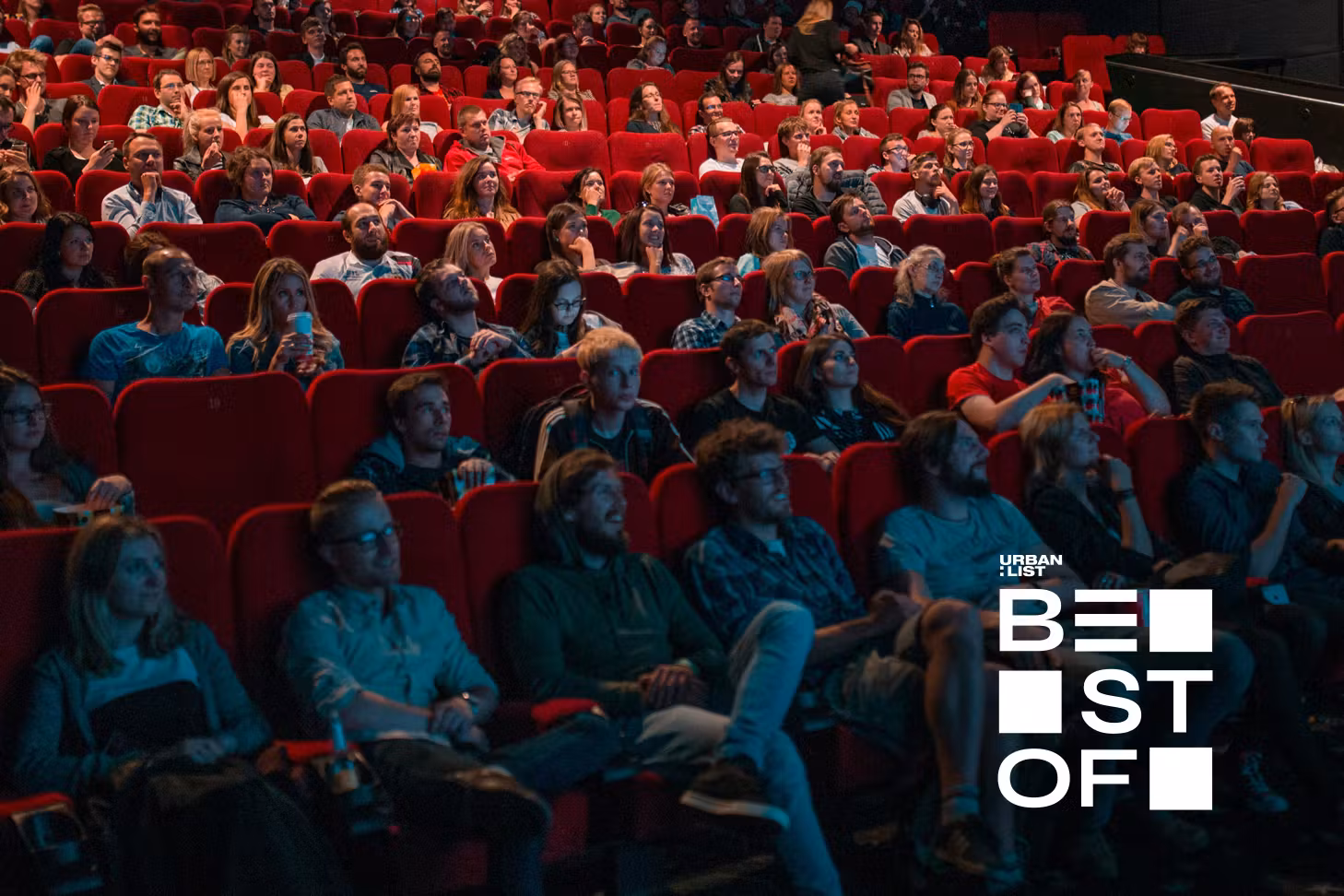 People have a good time at the cinema, sitting in plush red seats.